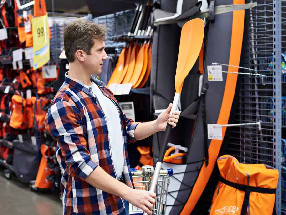 Man with a paddle for a sports boat kayak in a store