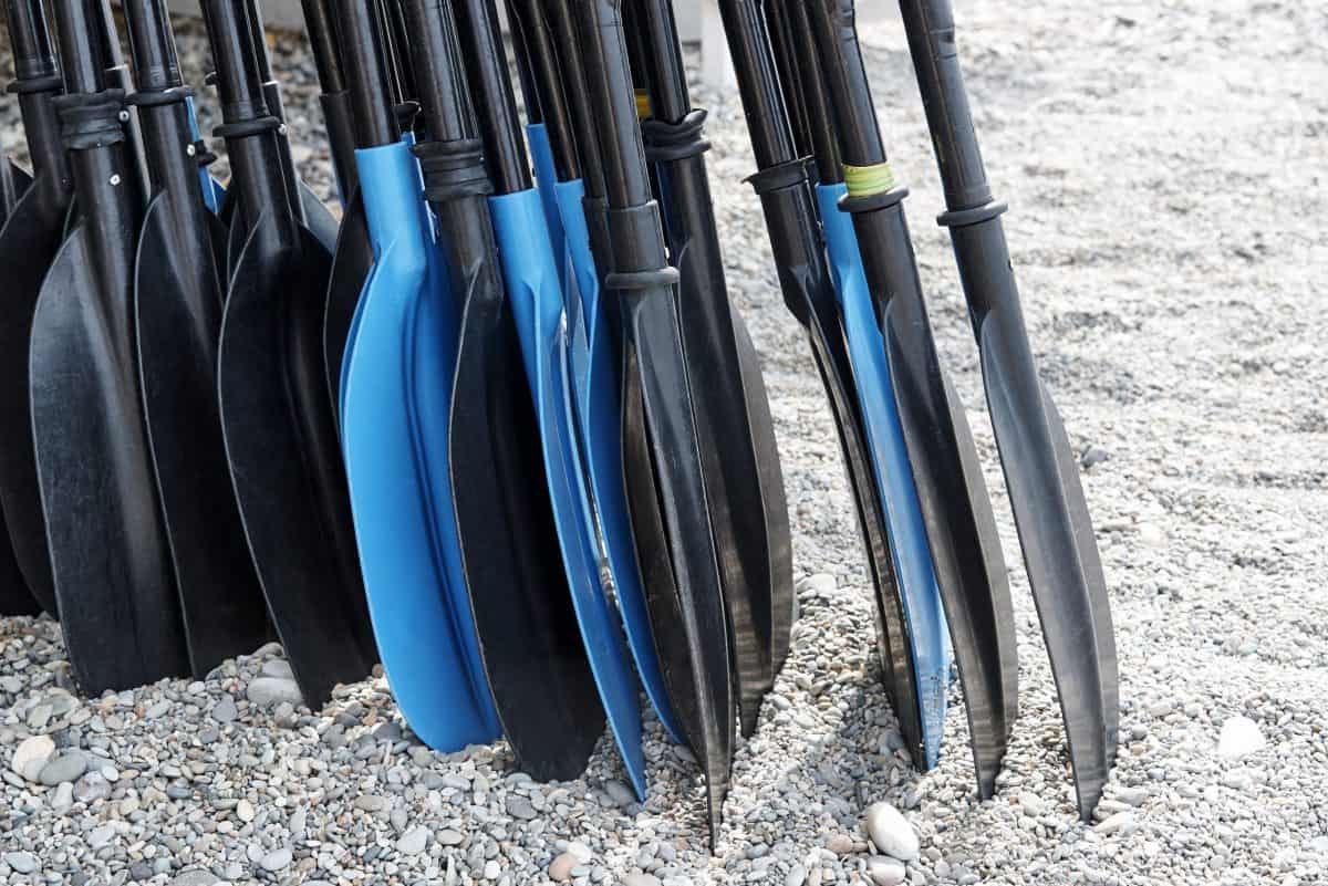 A pile of kayak paddles on the beach close up.