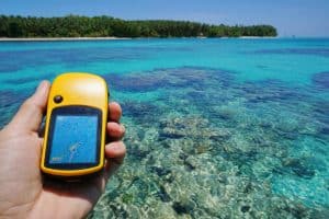 GPS satellite navigator in hand over tropical sea