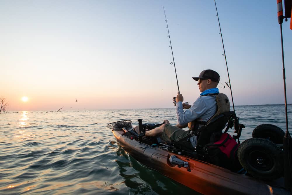 Man in kayak anchored fishing in lake