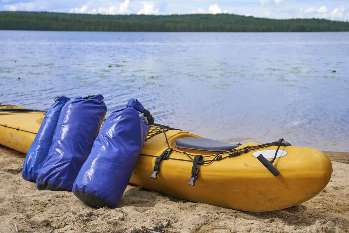 Two dry bag laying next to a yellow kayak