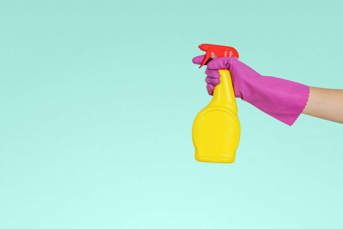 Hand in rubber glove holding a kayak wax spray bottle