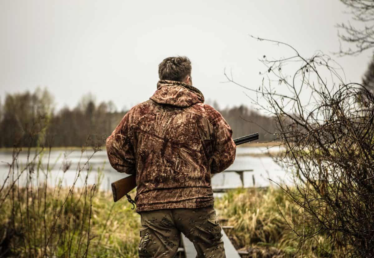 Hunter with a gun tracks down ducks on the river.