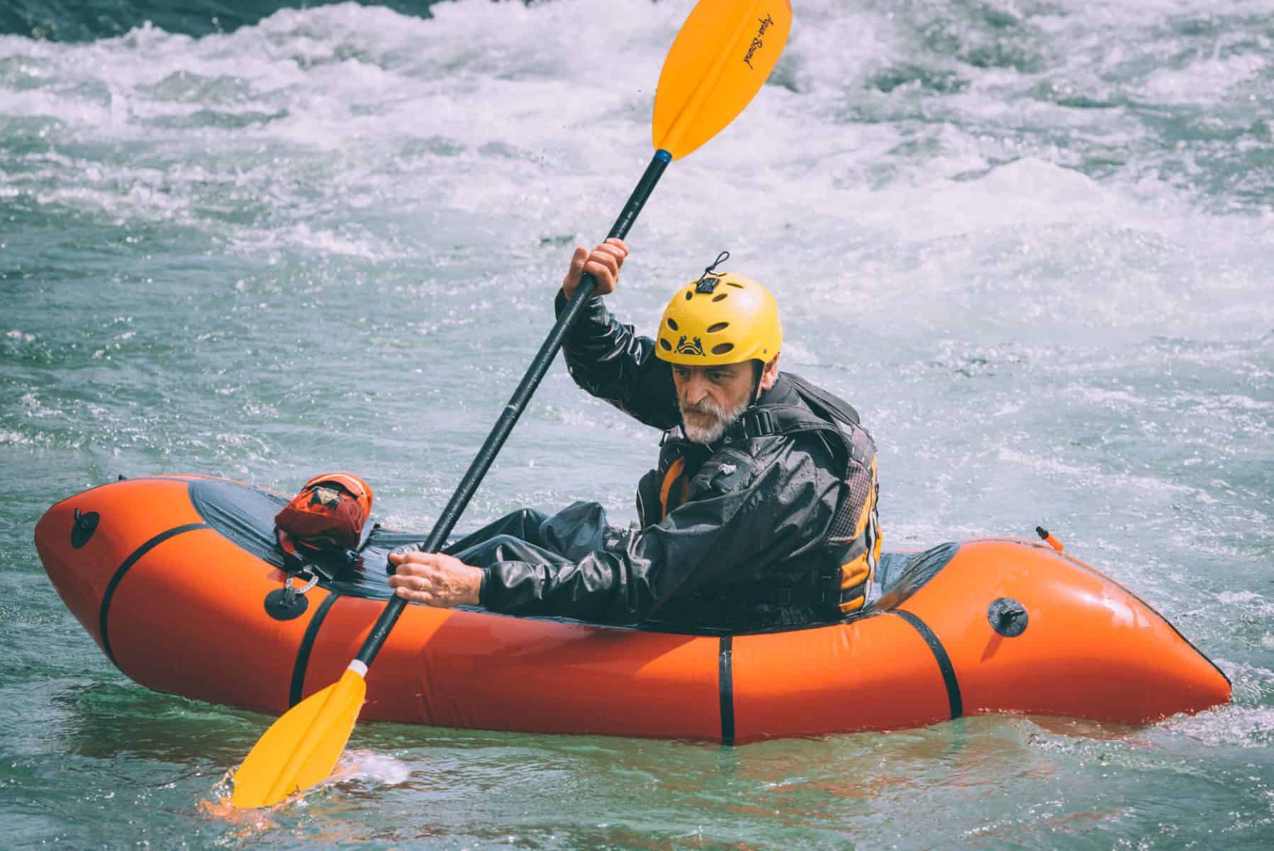 Man paddle orange whitewater kayak in drysuit