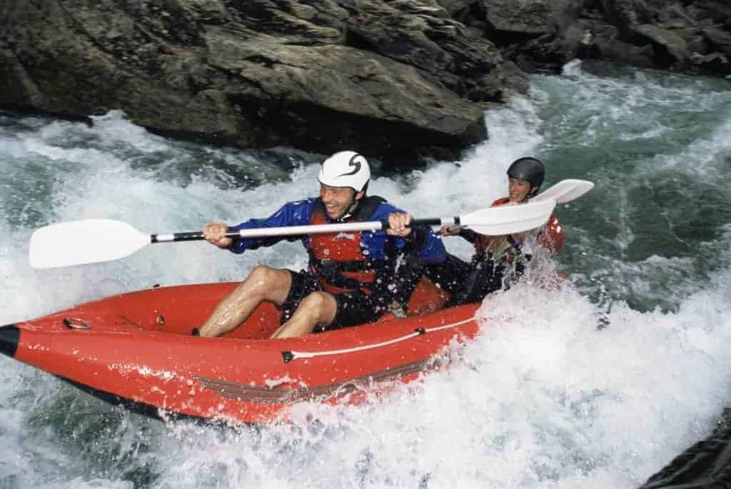 best inflatable kataks - man paddles in orange inflatable in rapids