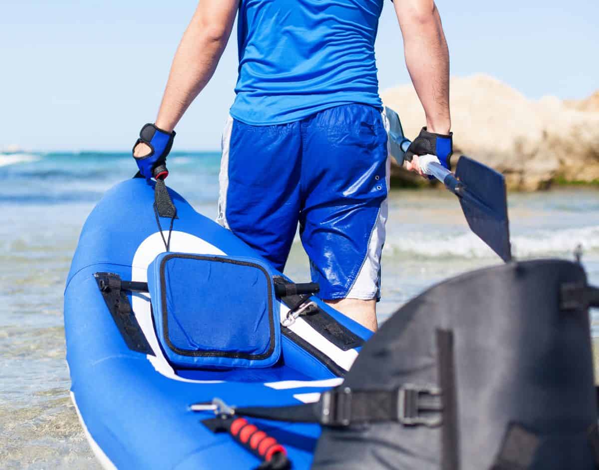 Man carrying blue inflatable kayak into the sea