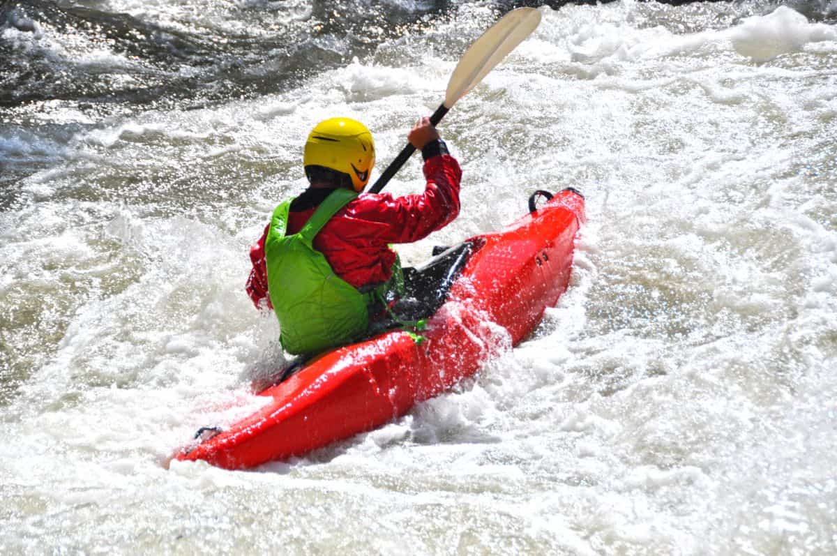 Paddler in red whitewater kayak battling extreme rapids