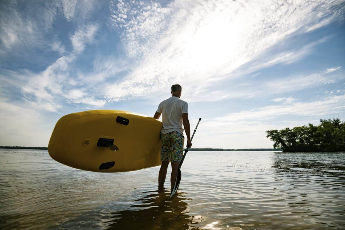 Happy man stands with a SUP board