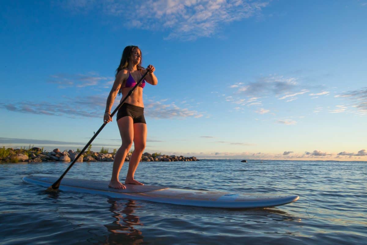 Woman stand up paddleboarding at sunrise on Ocean