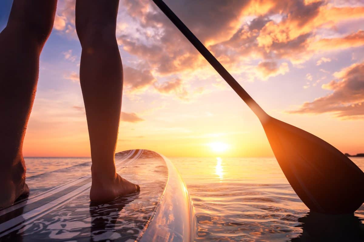 Inflatable stand up paddle boarding on quiet sea at sunset