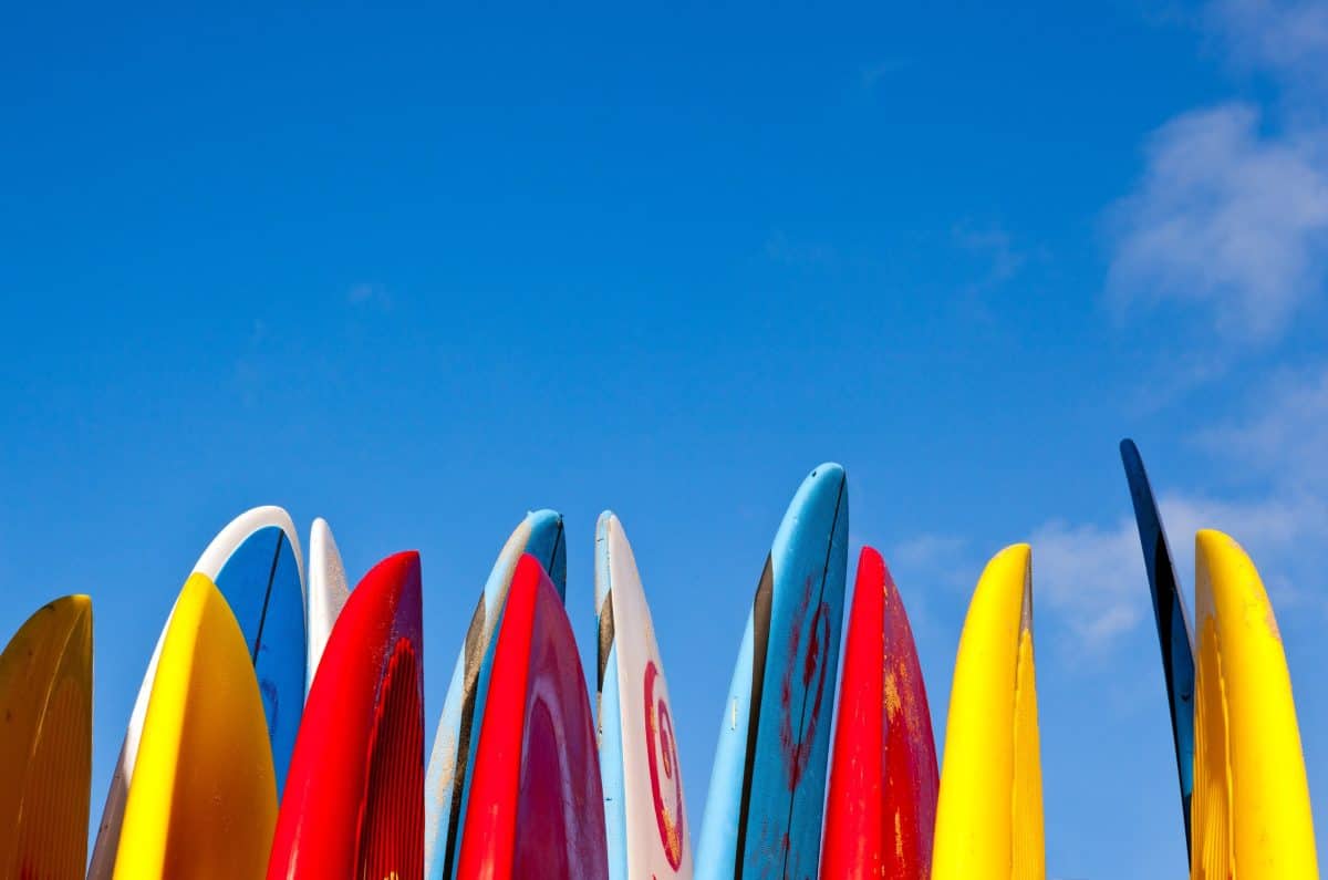 Set of different color SUP boards in a stack by ocean