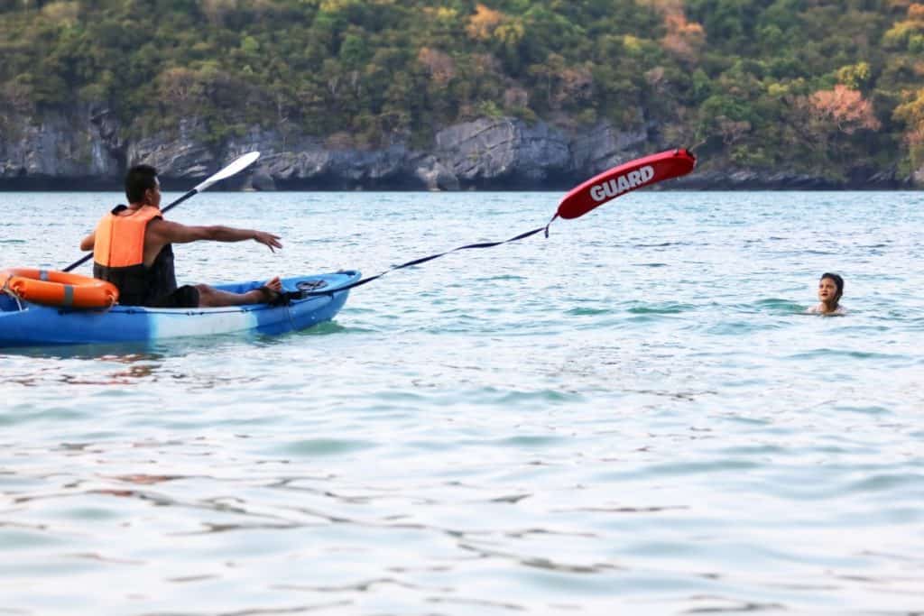 Father throws giant flotation device from kayak to son in the water